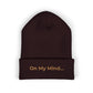 Brown cuffed beanie with gold “On My Mind...” embroidery on the front.