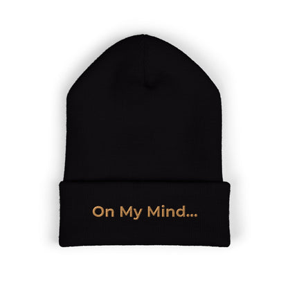 Black cuffed beanie with gold “On My Mind...” embroidery on the front.