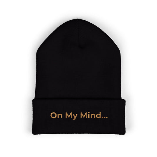 Black cuffed beanie with gold “On My Mind...” embroidery on the front.